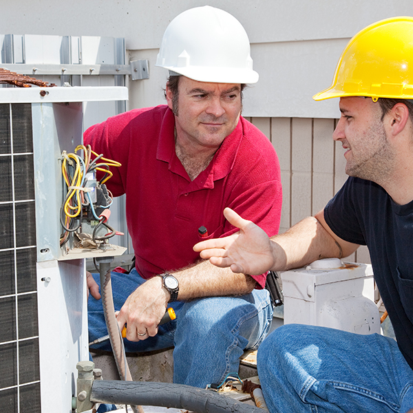 Air Conditioning, Refrigeration & Heating Residential HVAC technician training his HVAC helper perform preventive maintenance and minor repairs on air conditioner condenser.